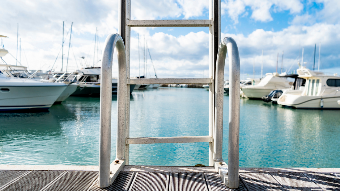 Ladder into the water of the little harbor of the marina of San Vincenzo, province of Livorno, Tuscany, Italy, with moored boat and yachts.